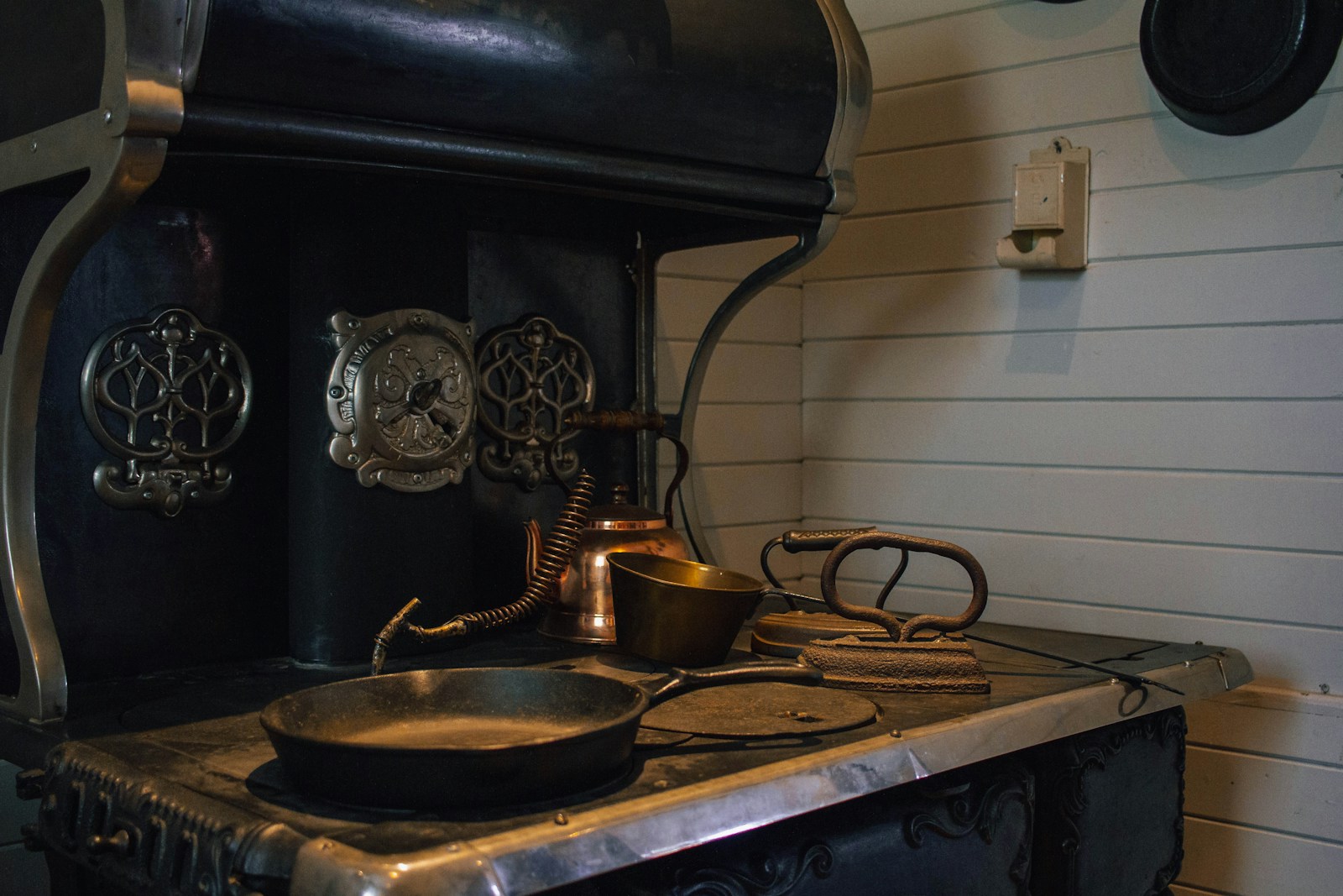 An antique cast iron stove with a skillet and kettle
