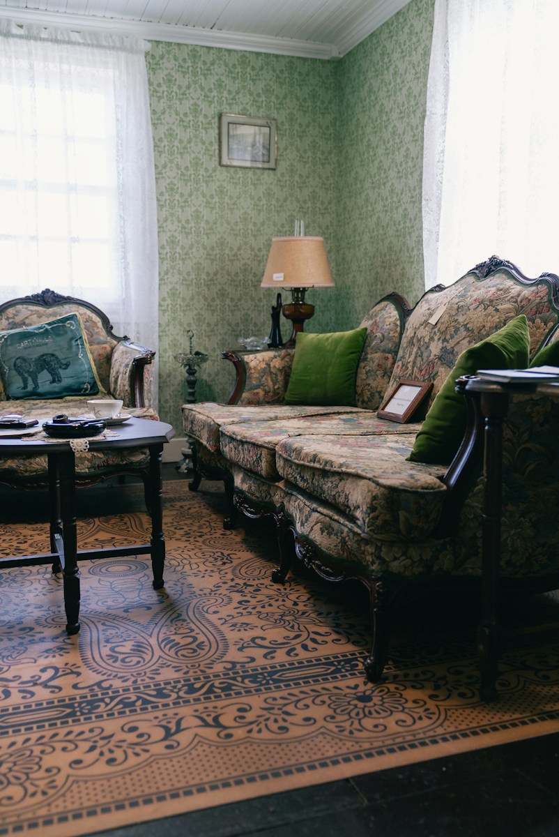 A vintage living room with ornate furniture and green wallpaper