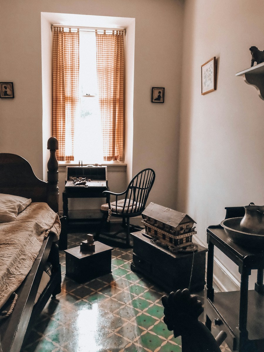 An old-fashioned room with a bed, desk, and patterned floor