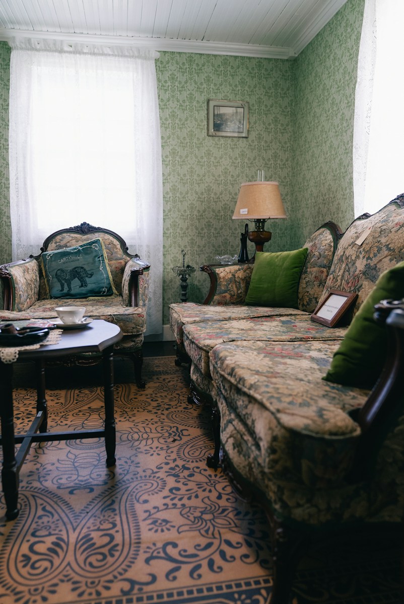 A vintage living room with green wallpaper and ornate furniture
